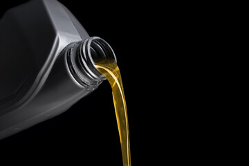 Pouring of motor oil from canister against black background, closeup