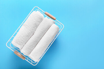 Basket with clean towels on blue background