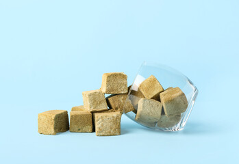Glass with tasty hojicha marshmallows on blue background