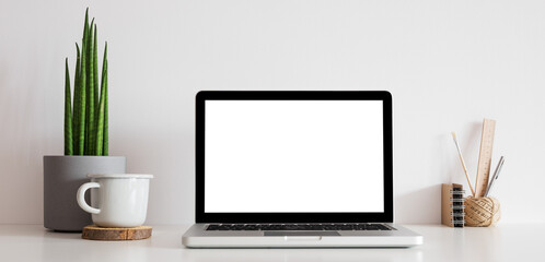 Laptop screen mockup at home office desk. Table with computer and accessories, books, school supplies. Stylish workspace. Banner. Mock up.	
