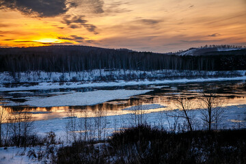 winter sunset on the river. reflection on the water and ice drift