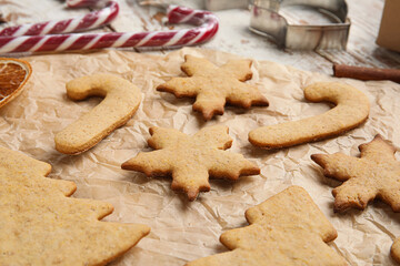 Parchment with Christmas gingerbread cookies on table, closeup