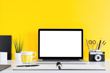 Yellow wall with laptop and school accessories. Creative workspace. Mockup.