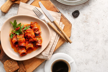 Plate with delicious prunes in crispy bacon, parsley and gravy on light table