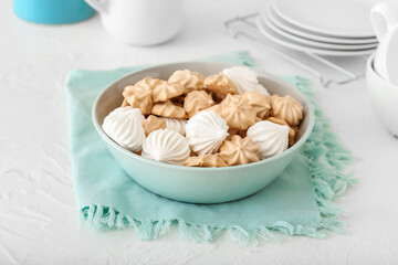 Bowl with tasty meringues on table
