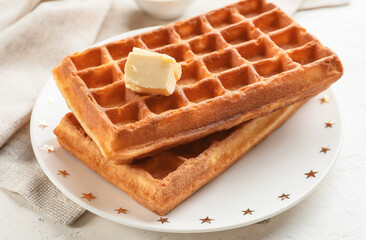 Plate with tasty Belgian waffles and butter on light background