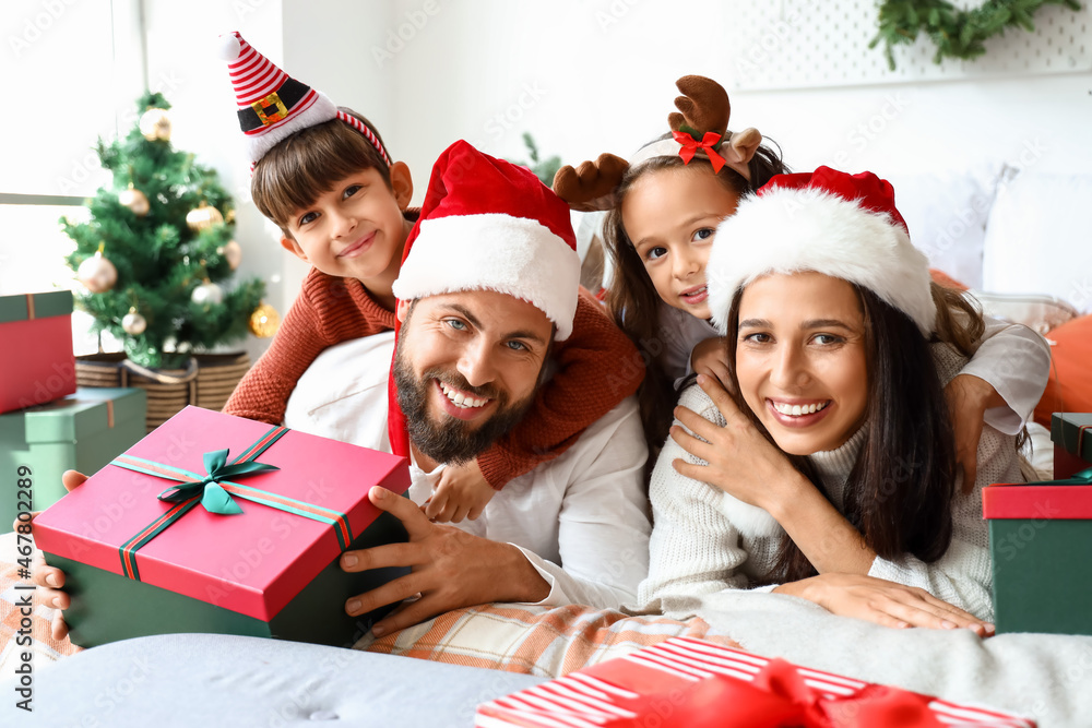 Poster Happy family with Christmas gifts lying on bed