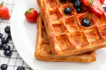 Plate of tasty Belgian Waffles with berries on table, closeup