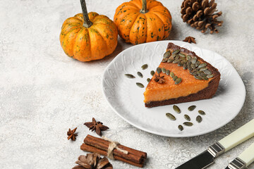 Plate with piece of delicious pumpkin pie on light background