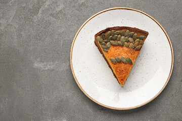 Plate with piece of delicious pumpkin pie on grey background