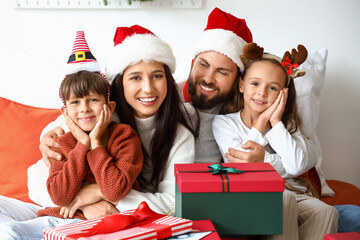 Happy family with Christmas gifts in bedroom