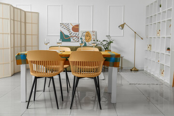 Dining table with bright cloth and chairs in modern room