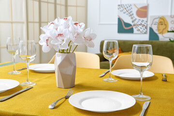 Vase with flowers on yellow tablecloth in modern room
