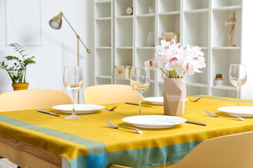 Vase with flowers on served table in modern room