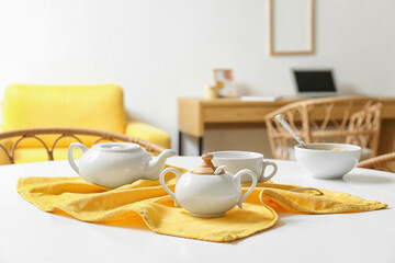 Fototapeta na wymiar Dining table with teapot and yellow napkin in room