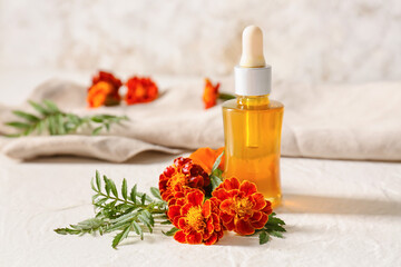 Bottle of essential oil and marigold flowers on table