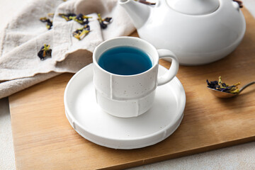 Fototapeta na wymiar Teapot and cup of organic blue tea on light background