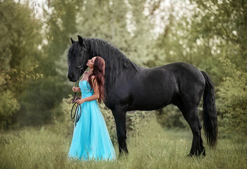 Beautiful long-haired girl in a dress next to a black horse