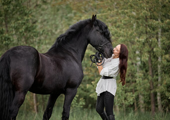 Beautiful long-haired girl with a Friesian horse