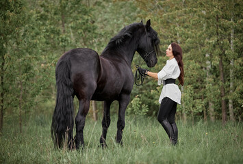 Beautiful long-haired girl with a Friesian horse