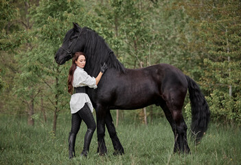 Beautiful long-haired girl with a Friesian horse