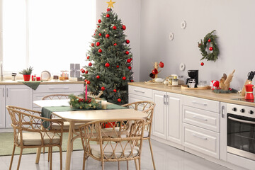 Interior of light kitchen with Christmas tree and dining table