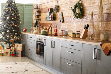Grey counters and Christmas tree near wooden wall in kitchen