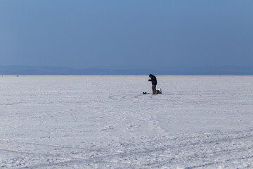 Fototapeta na wymiar Winter sea fishing in Vladivostok. A fisherman is fishing across the frozen sea.