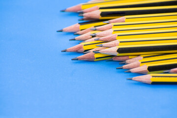 Yellow and black graphite pencils group close up on light blue background. Copy space concept