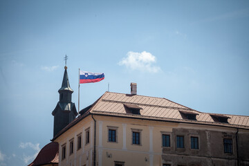 Flag of Slovenia waiving in the air with a sunny sky background on the Ljubljana Castle. Slovenia,...