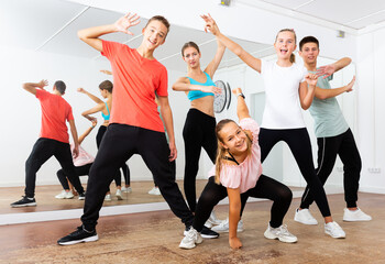 Group portrait of fine teenagers with young female choreographer in modern dance studio
