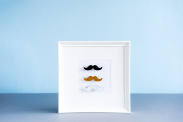 Different color male moustaches in the photo frame on the blue background. Men health awareness month, fathers day masculinity concept. Male Diversity. Face hair Fashion. Selective focus, Copy space.
