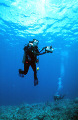 Fototapeta na wymiar A Hawaiian Tropical Scuba Diver Woman with a Video Camera Ascending After a Successful Dive