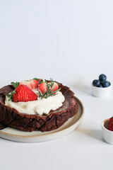 Chocolate flourless cake with strawberries, blueberries and whipping cream. Fresh delicious homemade bakery. 