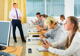 Obraz premium Schoolchildren with mobile phones in informatics lesson in class