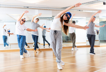 Fototapeta na wymiar Happy smiling teenagers practicing vigorous hip hop movements in dance class