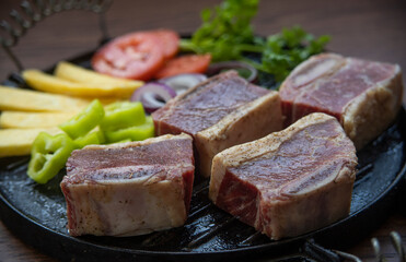 BEEF CUT INTO PIECES, WITH VEGETABLES SUCH AS TOMATO, ONION, PARSLEY, PEPPERS AND POTATOES, ON GRILL, READY TO BRING TO THE FIRE