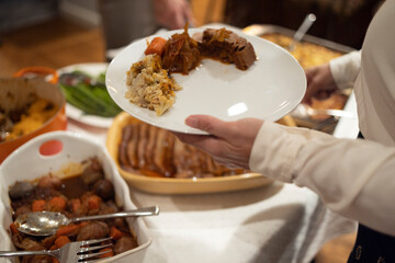 Person serving themselves food for Thanksgiving potluck meal