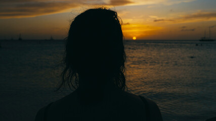 Woman looking out over the ocean on a tropical beach in deep contemplation