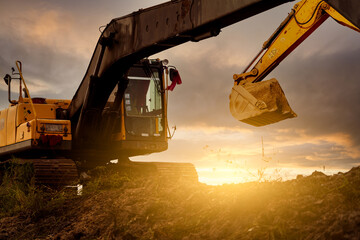Backhoe at construction site digging soil with bucket of backhoe. Bulldozer on sunset sky. Digger...