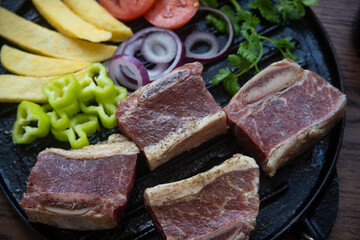 BEEF CUT INTO PIECES, WITH VEGETABLES SUCH AS TOMATO, ONION, PARSLEY, PEPPERS AND POTATOES, ON GRILL, READY TO BRING TO THE FIRE