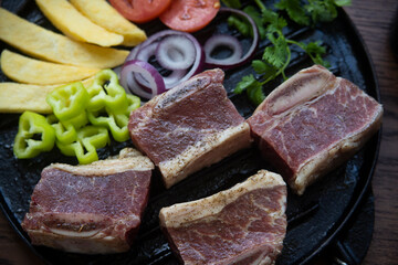 BEEF CUT INTO PIECES, WITH VEGETABLES SUCH AS TOMATO, ONION, PARSLEY, PEPPERS AND POTATOES, ON GRILL, READY TO BRING TO THE FIRE