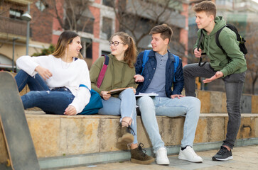 Company of teenagers are communicating on walk on the street