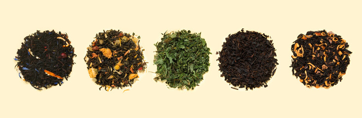 Large assortment of fresh fermented tea made from flowers, herbs, leaves and berries on yellow paper background.
