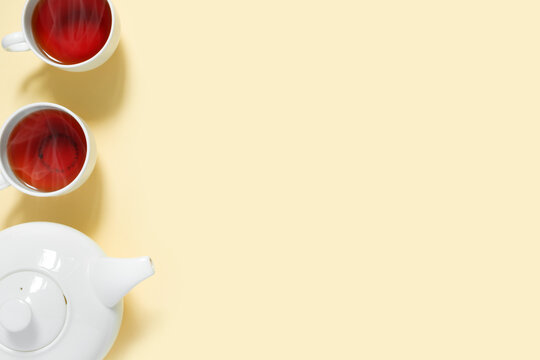 Teapot And Two Cups Of Hot Aromatic Tea On  Yellow Background. View From Above.