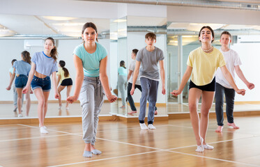 Positive smiling slim teenagers dancing hip hop in dance class