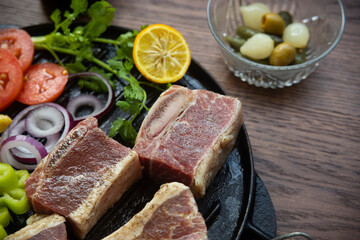 BEEF CUT INTO PIECES, WITH VEGETABLES SUCH AS TOMATO, ONION, PARSLEY, PEPPERS AND POTATOES, ON GRILL, READY TO BRING TO THE FIRE