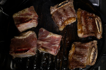 BEEF ON GRIDDLE CUT INTO CHUCKS COOKING ON A SLOW FIRE, WITH DARK FOOD TECHNIQUE AND SPACE FOR TEXT