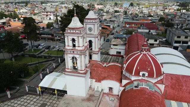 Church in State of Mexico on the day with blue sky and white clouds, cinematic aerial footage with drone in a small town with decoration of tematic party of saints