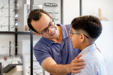 Indian father and son choosing eyeglasses in optics store
